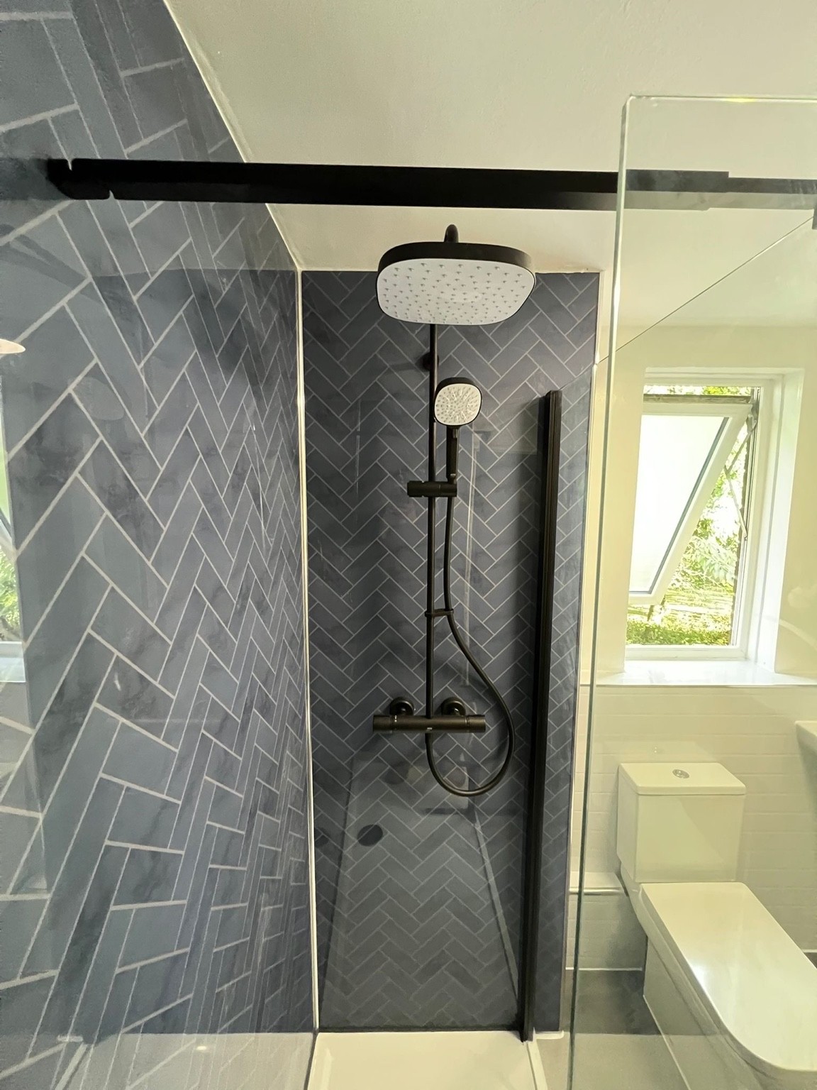 Navy herringbone tile shower with black fixtures